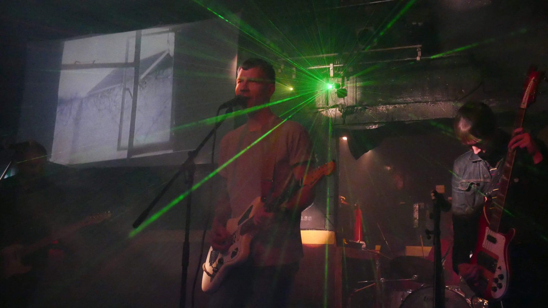 A man is singing into a microphone while playing a guitar on stage.