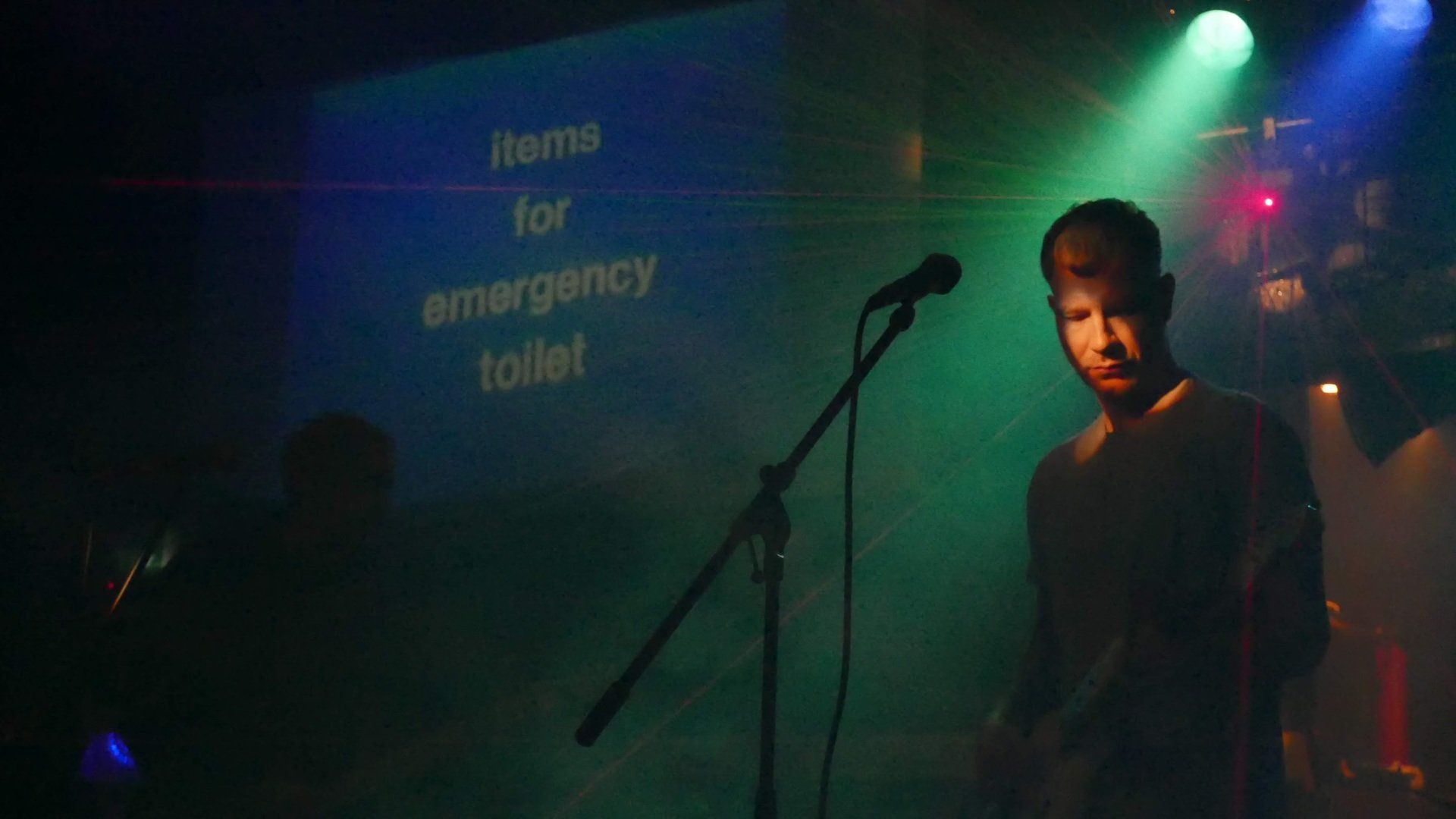 A man is playing a guitar and singing into a microphone on a stage.