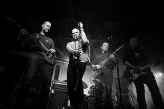 A black and white photo of a band playing instruments on stage.