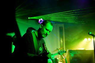 A man is playing a guitar and singing into a microphone on a stage.