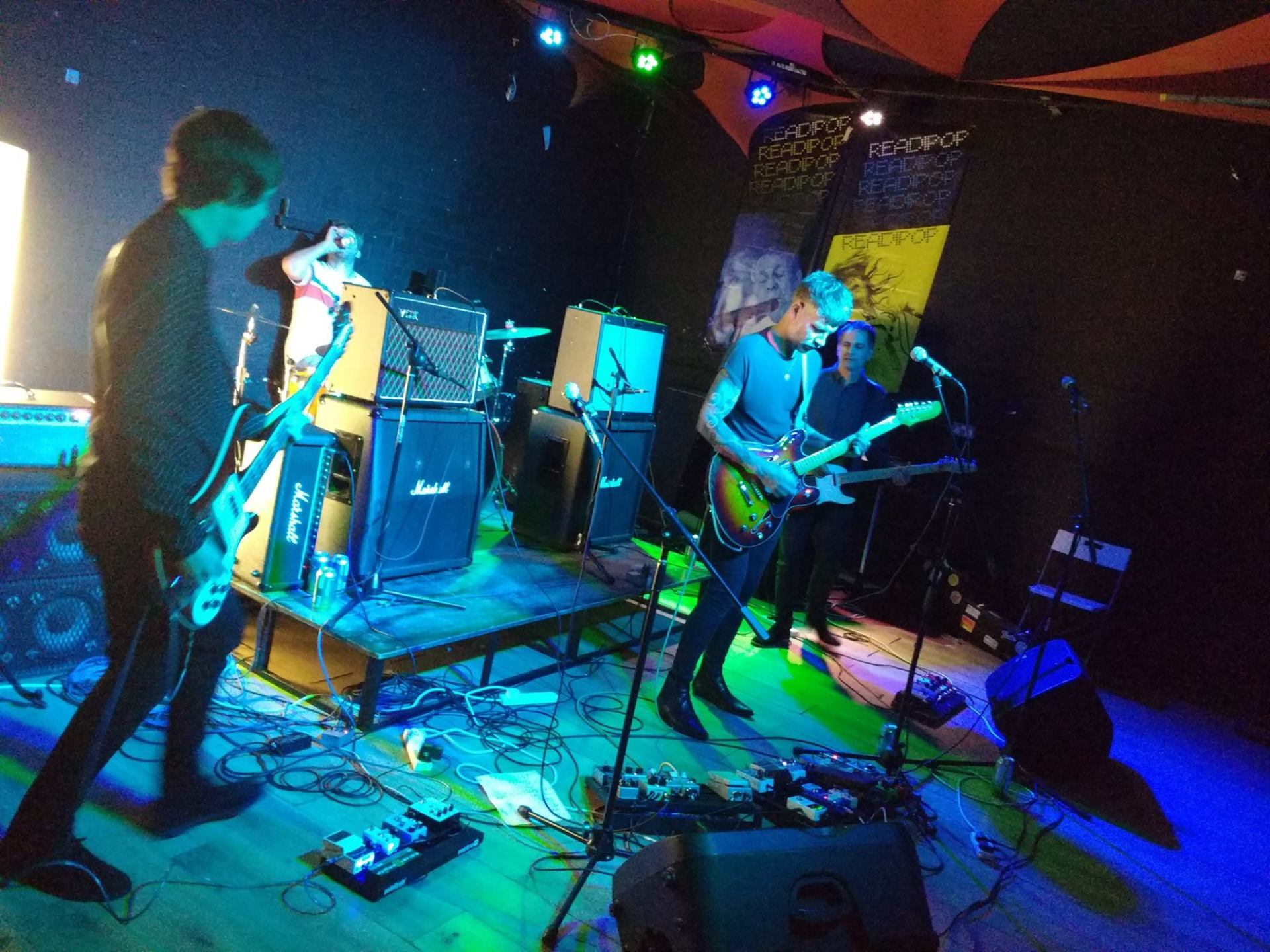 A group of people playing instruments on a stage in a dark room