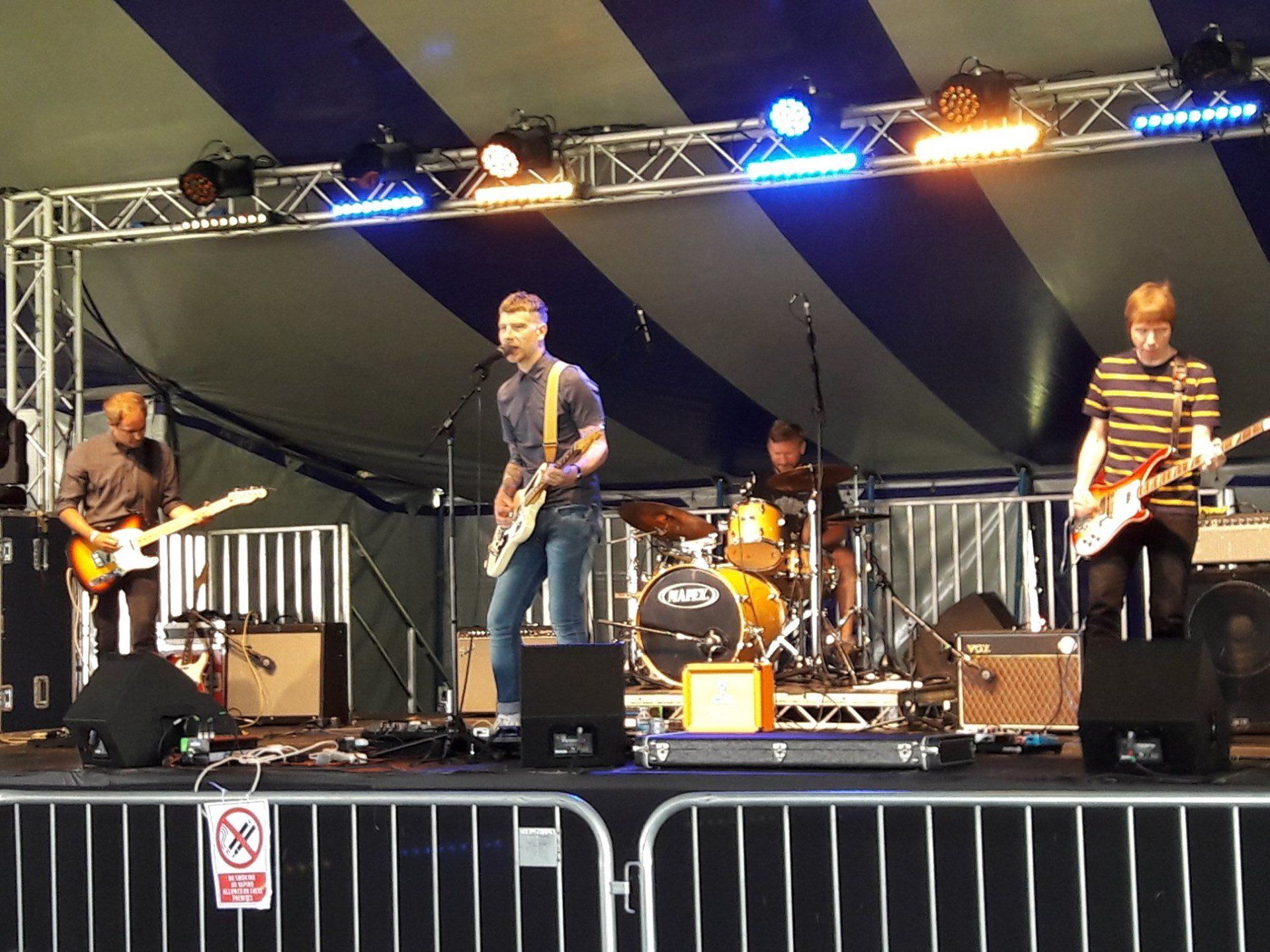 A band is playing on a stage under a striped tent