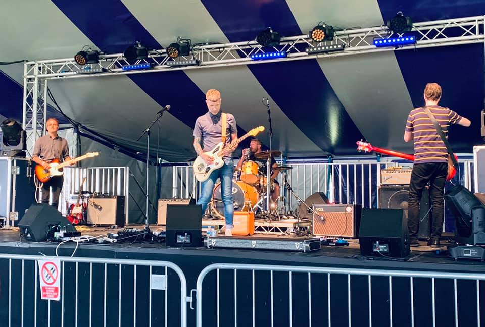 A group of men are playing guitars and drums on a stage.