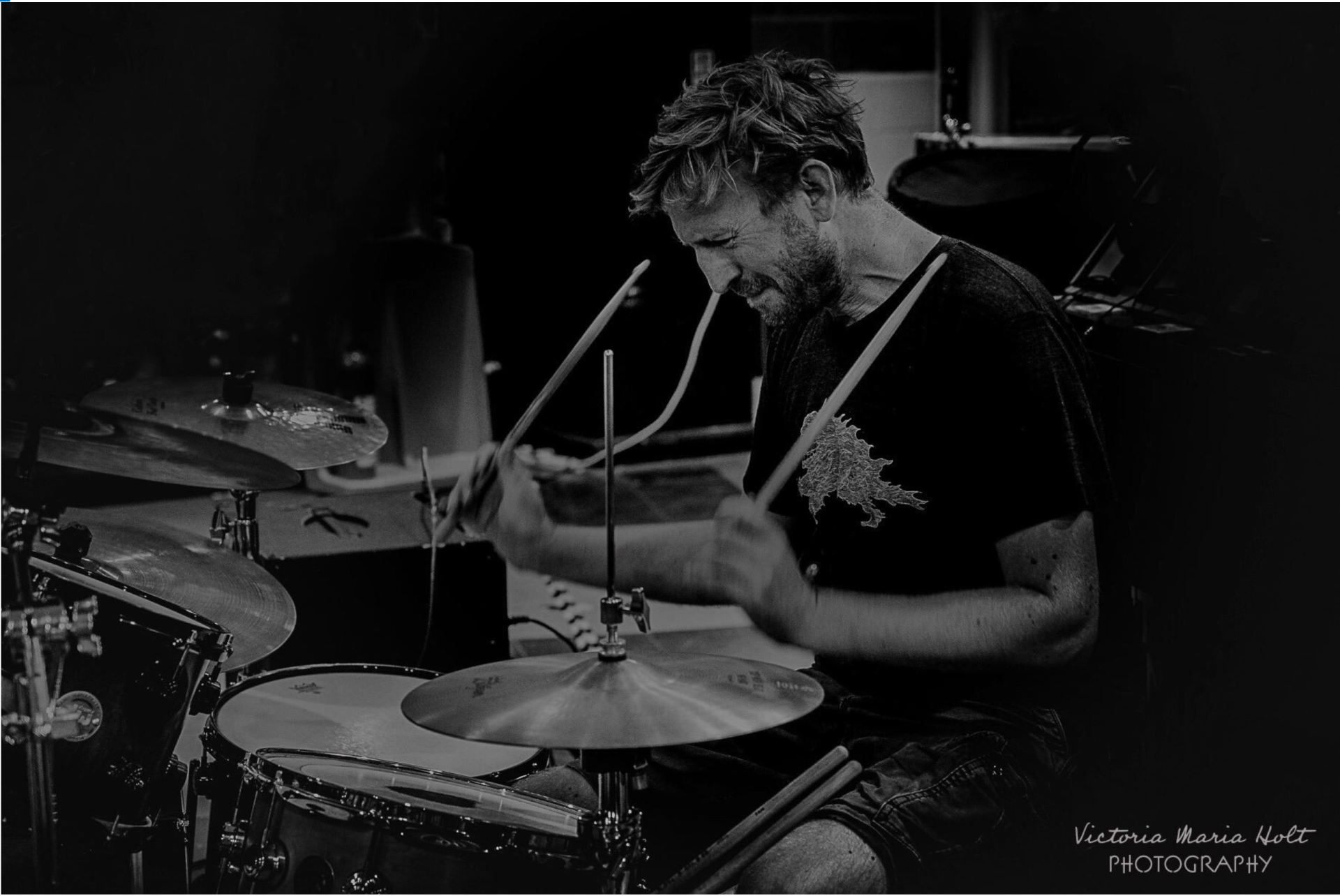 A man is playing drums in a black and white photo.