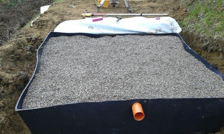 Un grande contenitore nero pieno di ghiaia e un tubo.