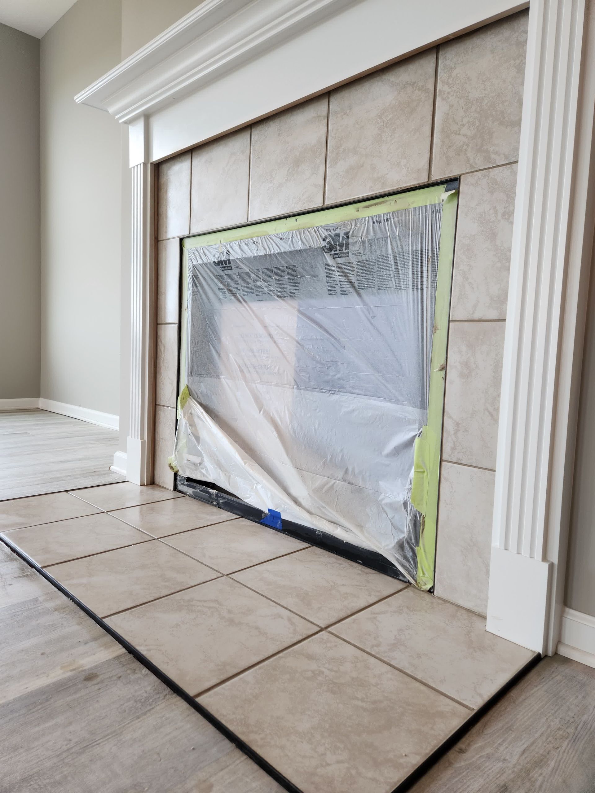 A man is laying a tile floor in a room.