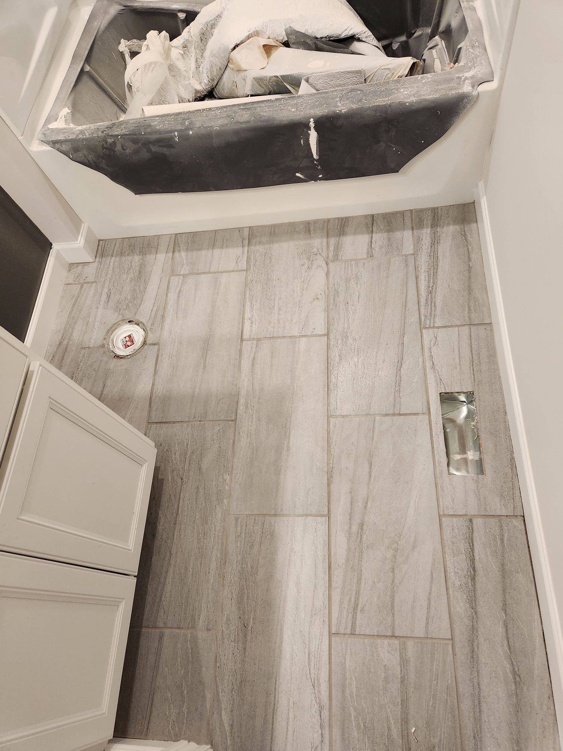 A man is laying a tile floor in a room.