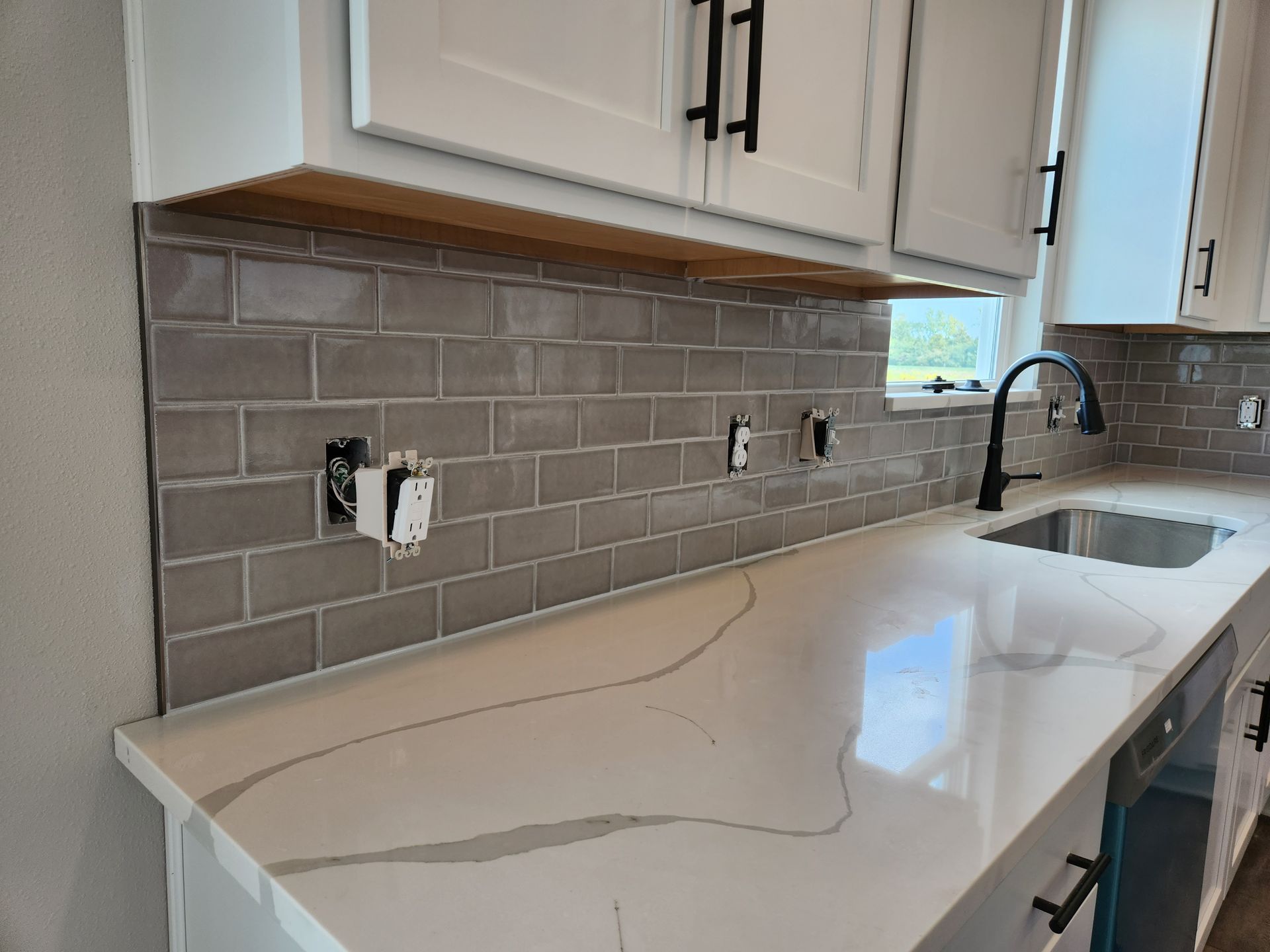 A kitchen counter with a red toaster , a kettle , and a basket of bananas.