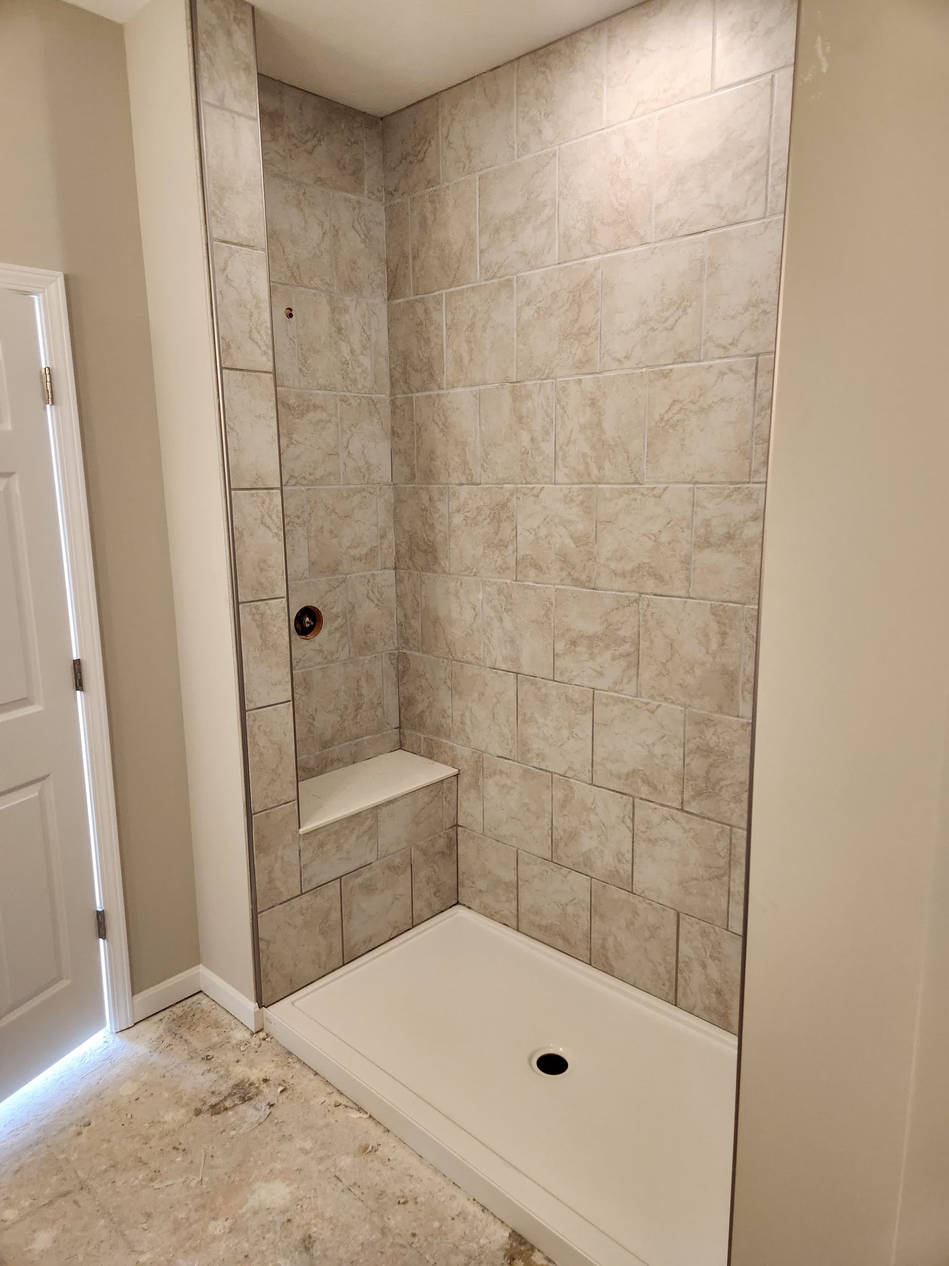 A man is applying tile adhesive to a tile floor.