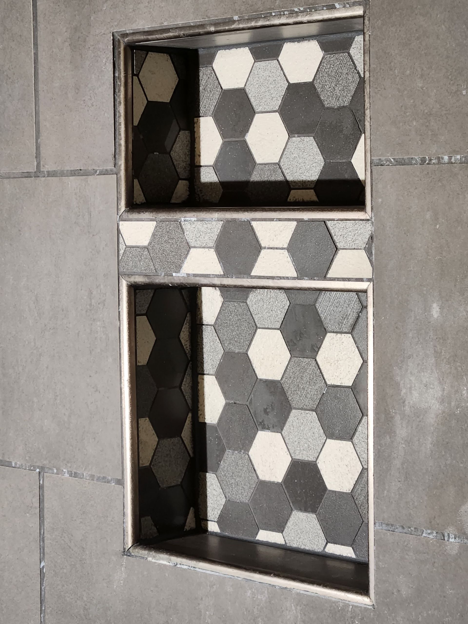 A person is laying tiles on a wall with a trowel.