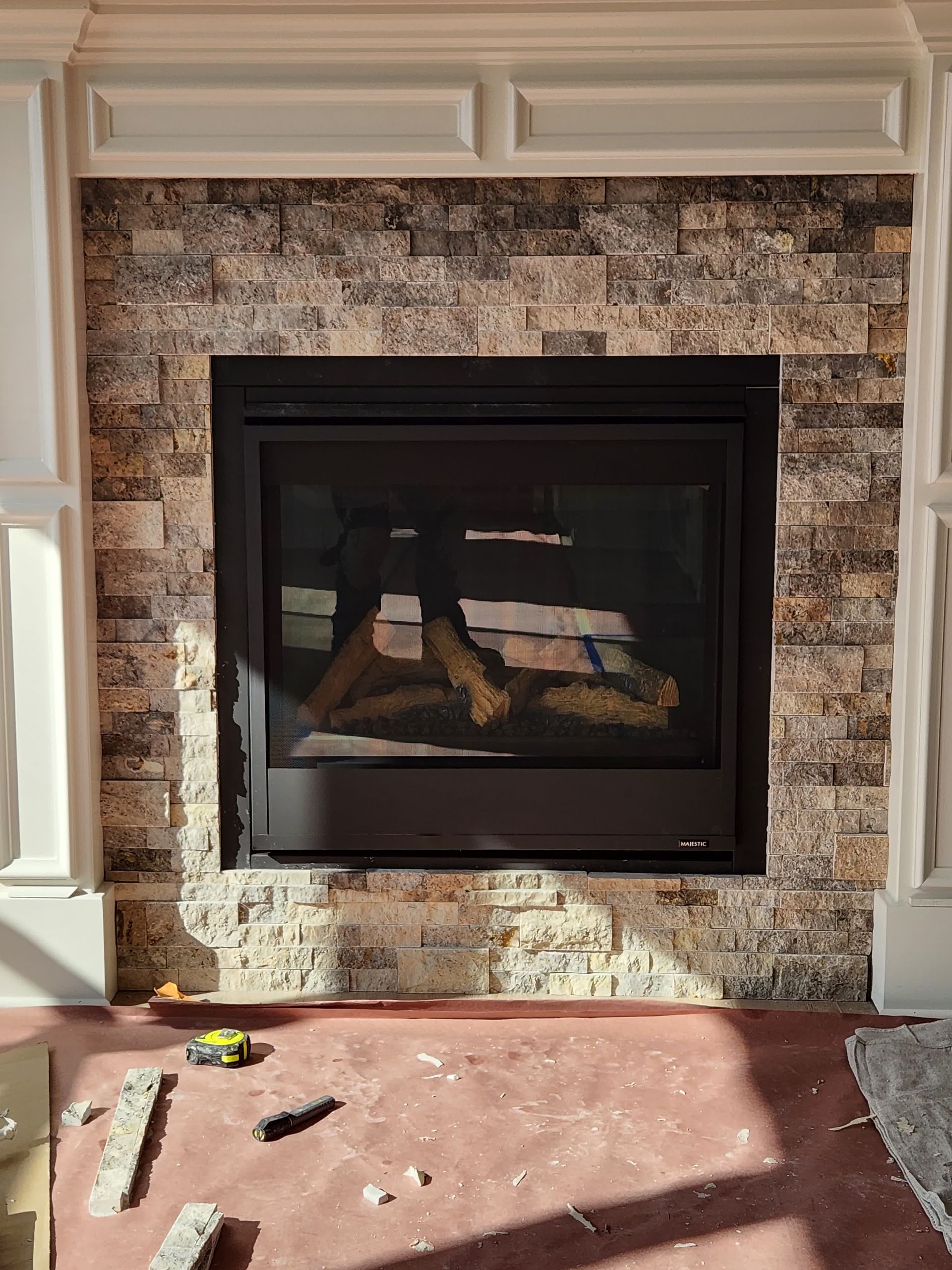 A fireplace is being installed in a living room with a brick wall.