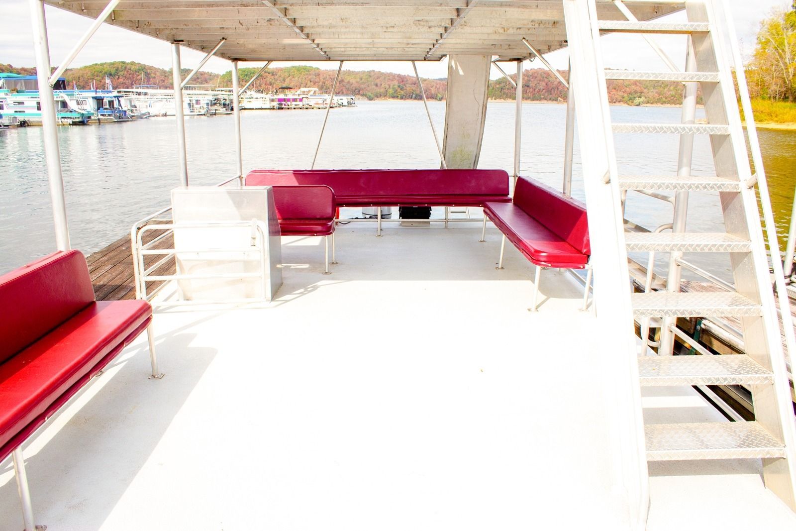 White boat deck with red seating; lake in background, ladder on right.