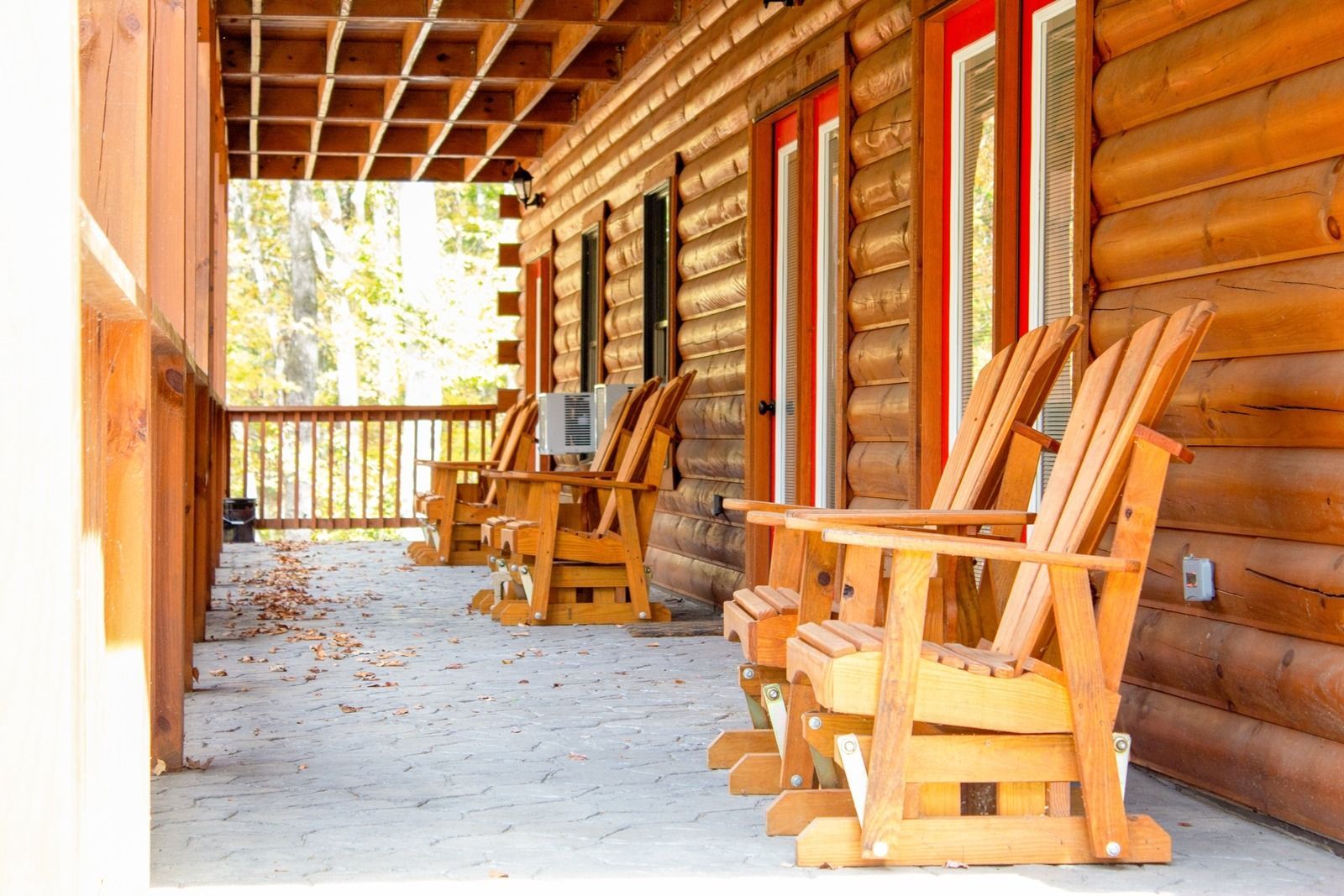 Wooden rocking chairs on a covered porch of a log cabin.