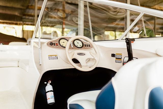 Boat's helm with a white steering wheel, gauges, and throttle; blue and white seat visible.
