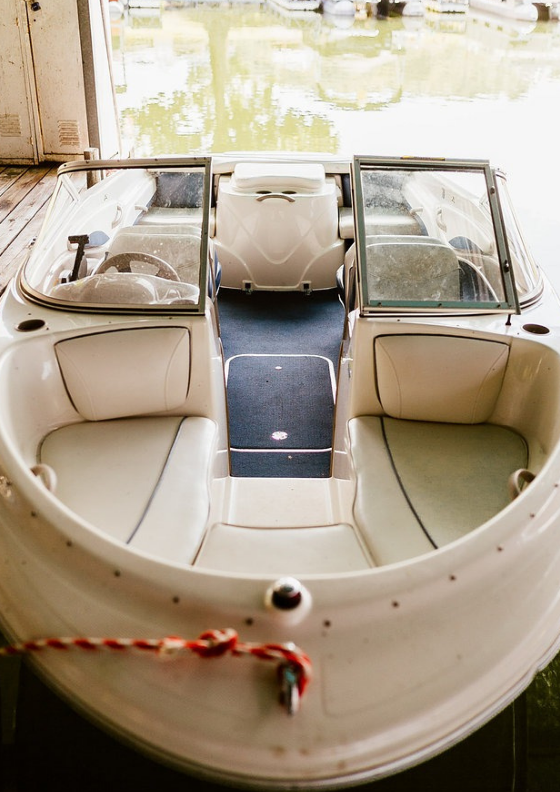 White motorboat interior with light seats, blue floor, and windscreen, docked.