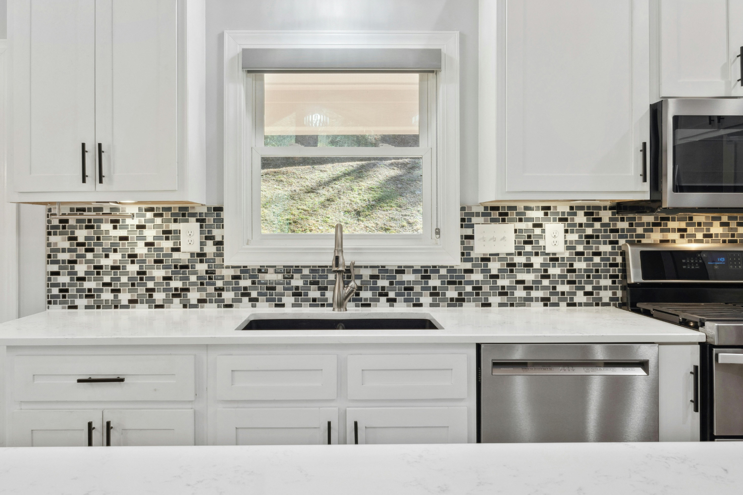 Kitchen backsplash with a sink, dishwasher, cabinets, and stove. 