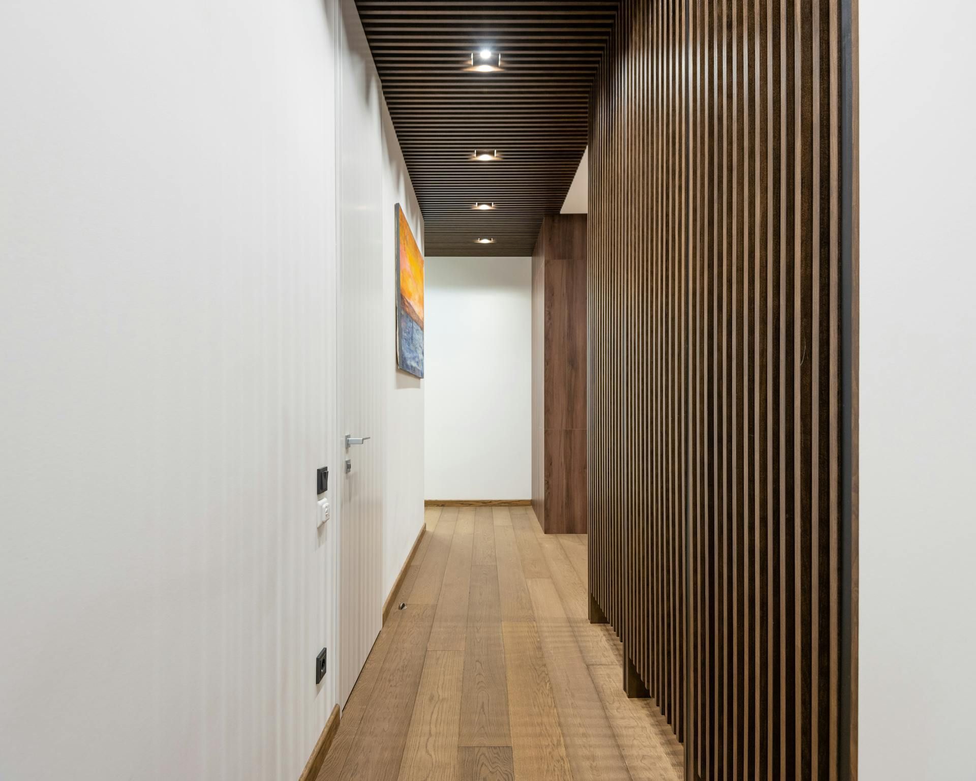A long hallway with a wooden divider and a painting on the wall.