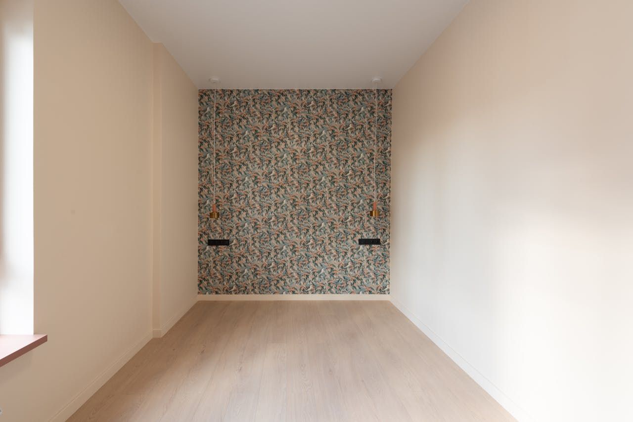 An empty room with a patterned wallpaper on the wall.