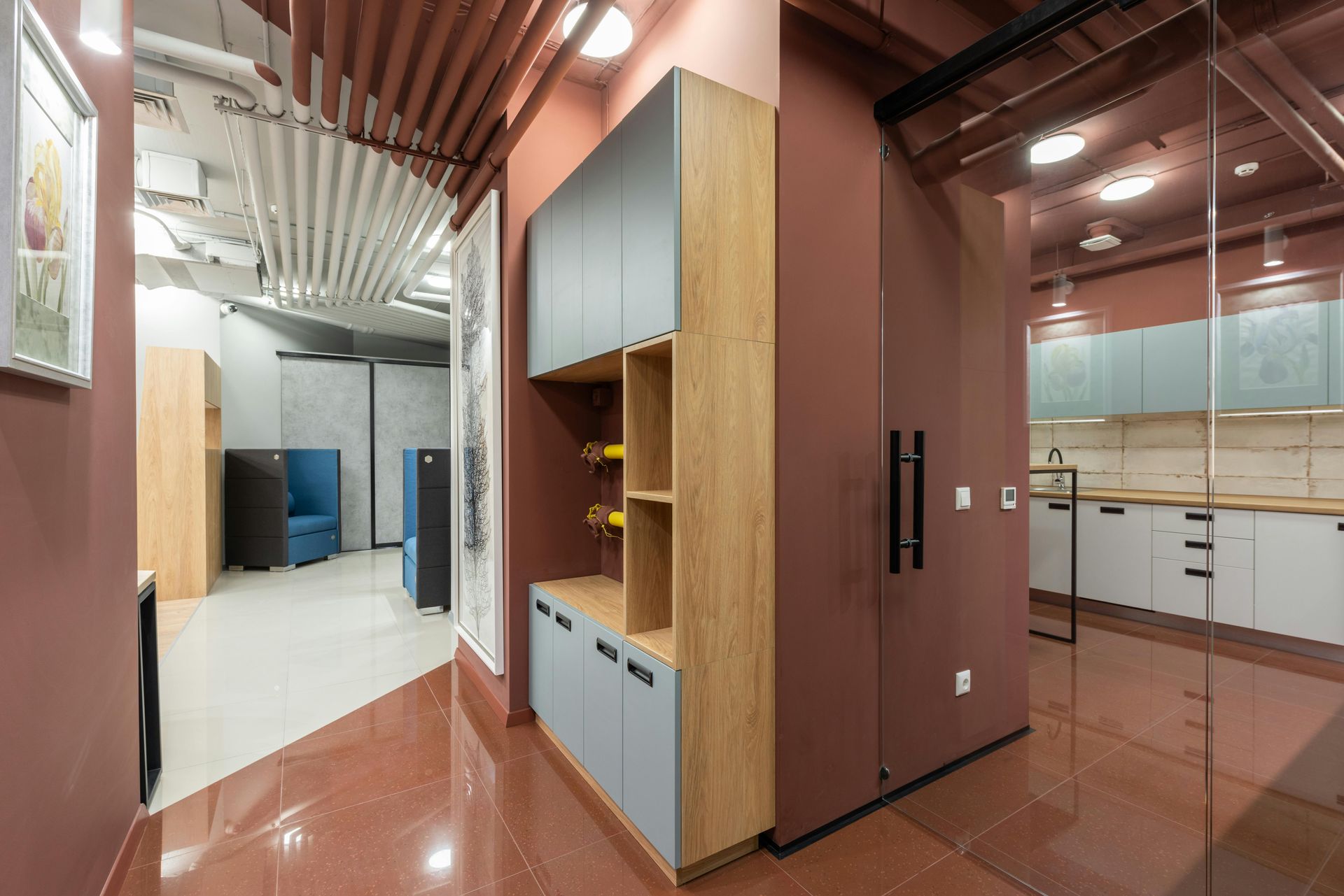 A hallway in an office building with a glass door leading to a kitchen.