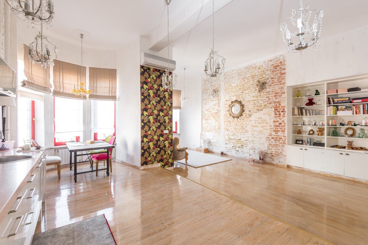 A living room with hardwood floors , a table and chairs , and a brick wall.