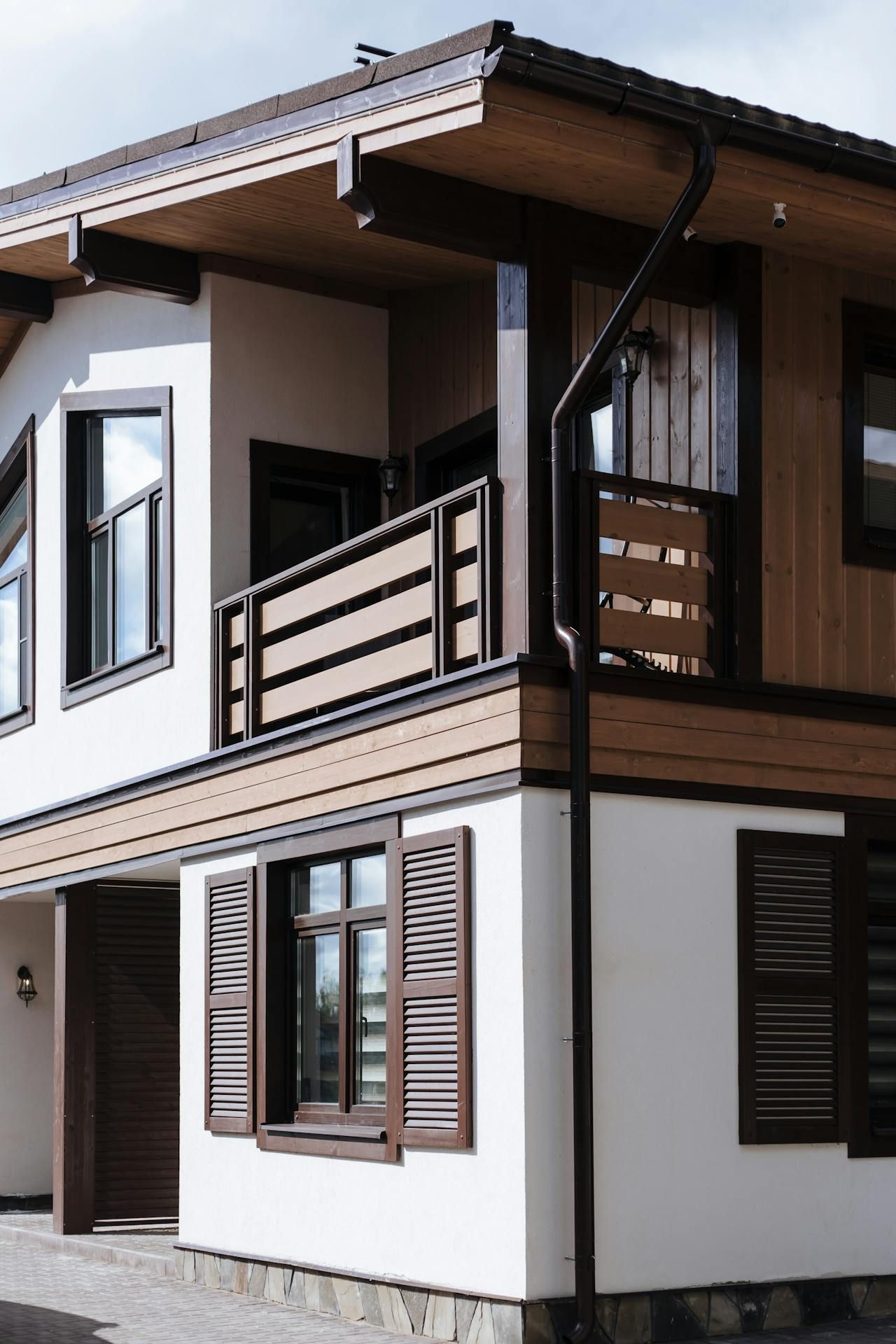 A white house with a balcony and shutters on the windows