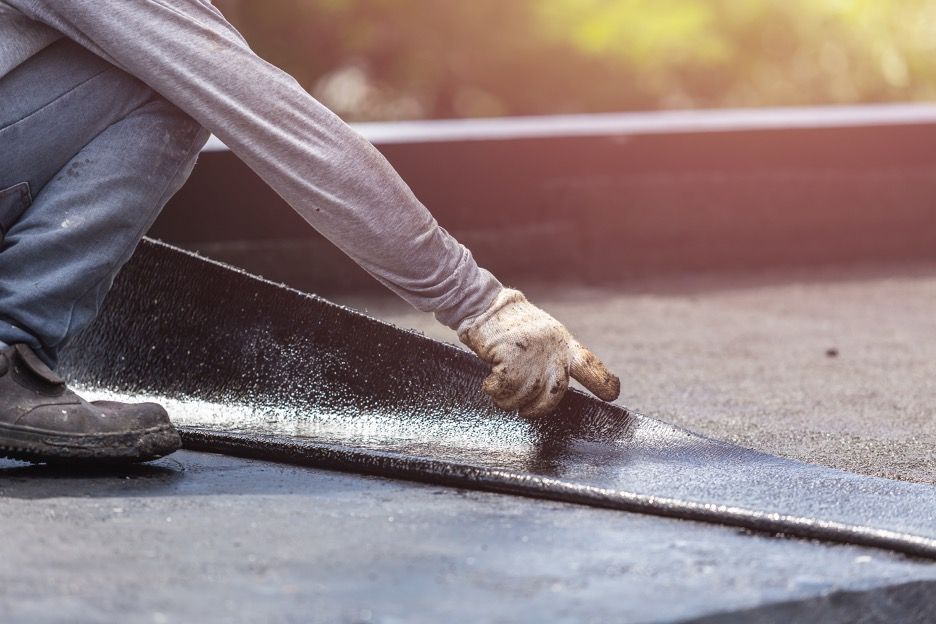 A man is applying a roof coating to a roof.