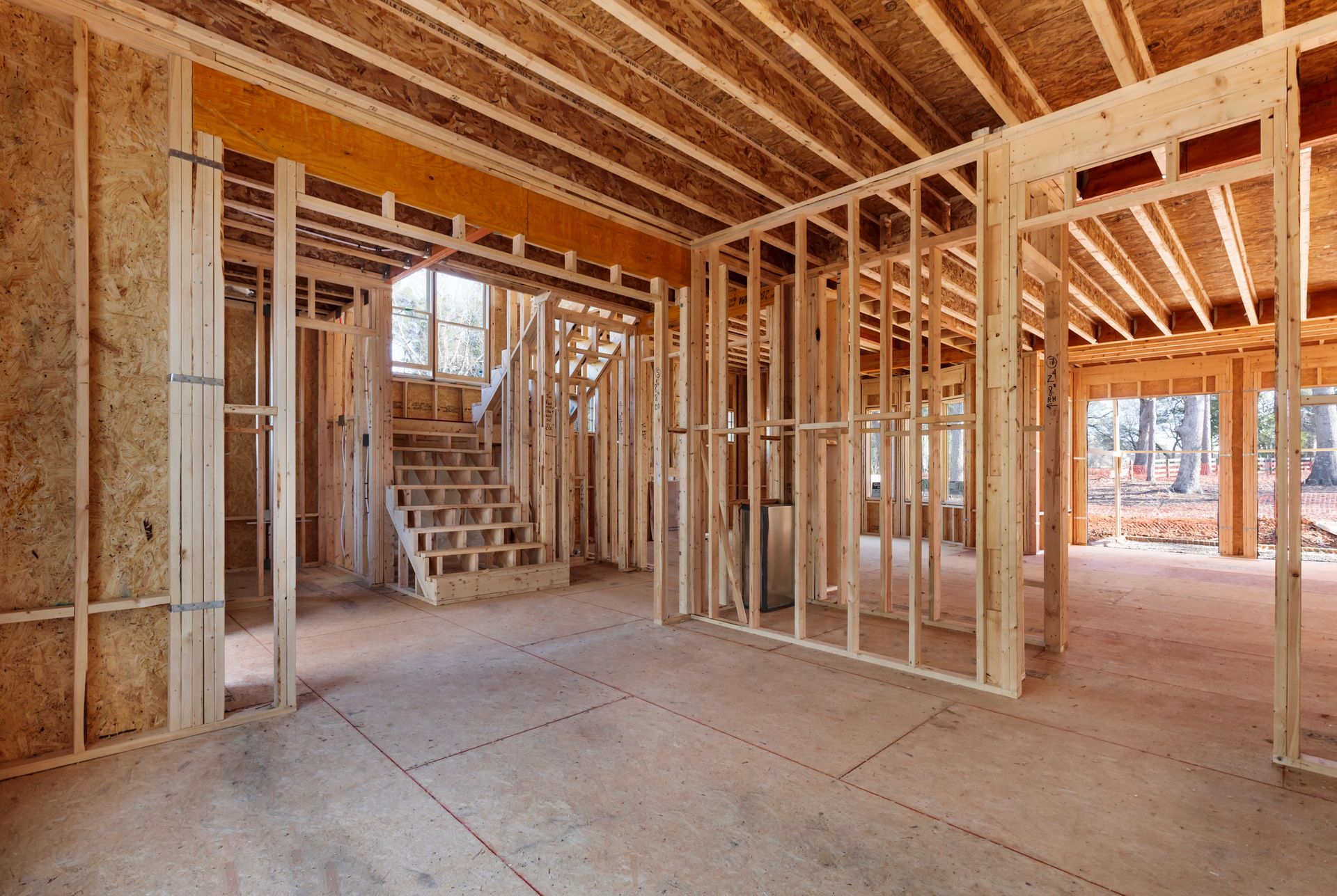 The inside of a house under construction with wooden beams and stairs.