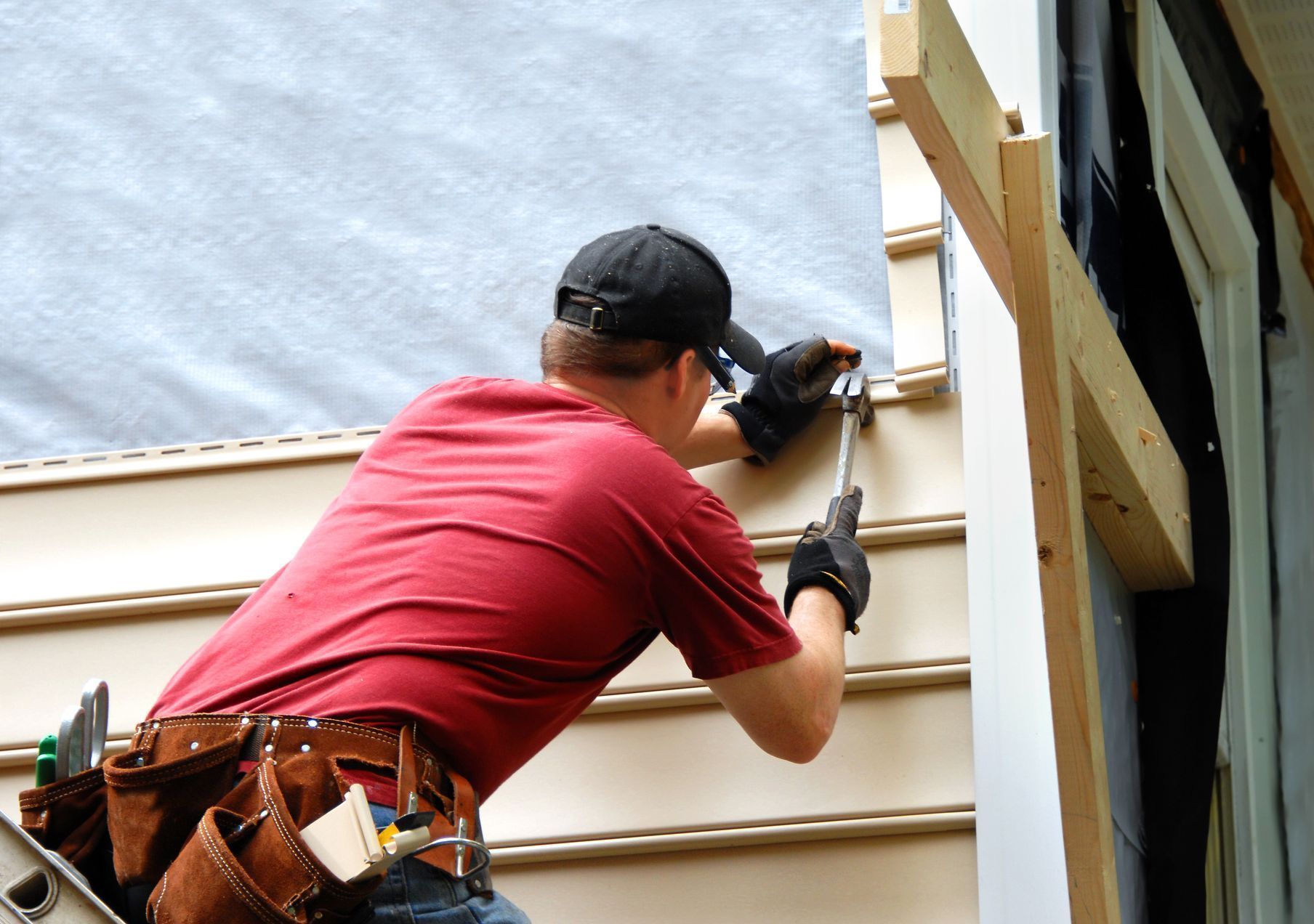 A man in a red shirt is working on the side of a building