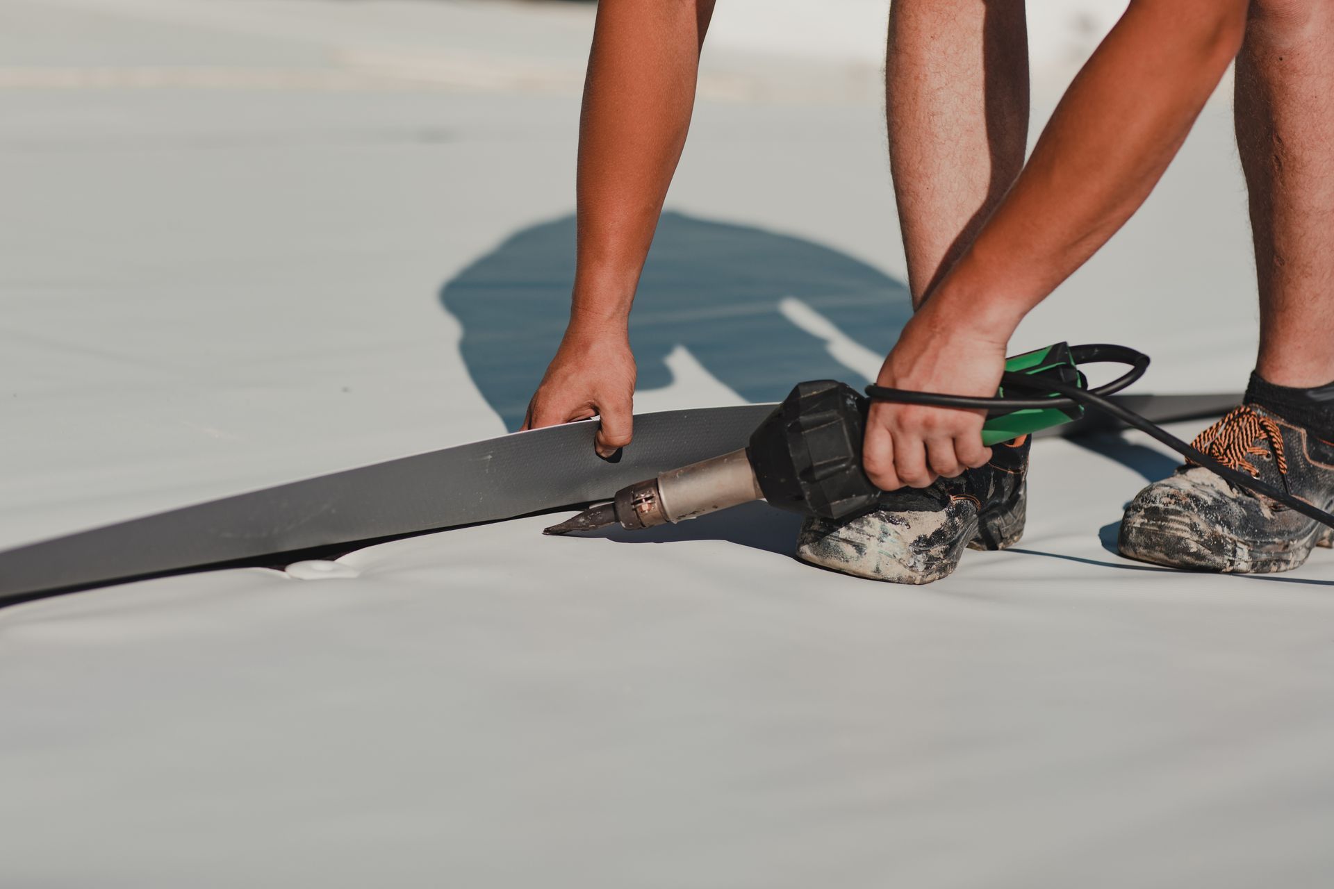 A man is working on a roof with a tool.