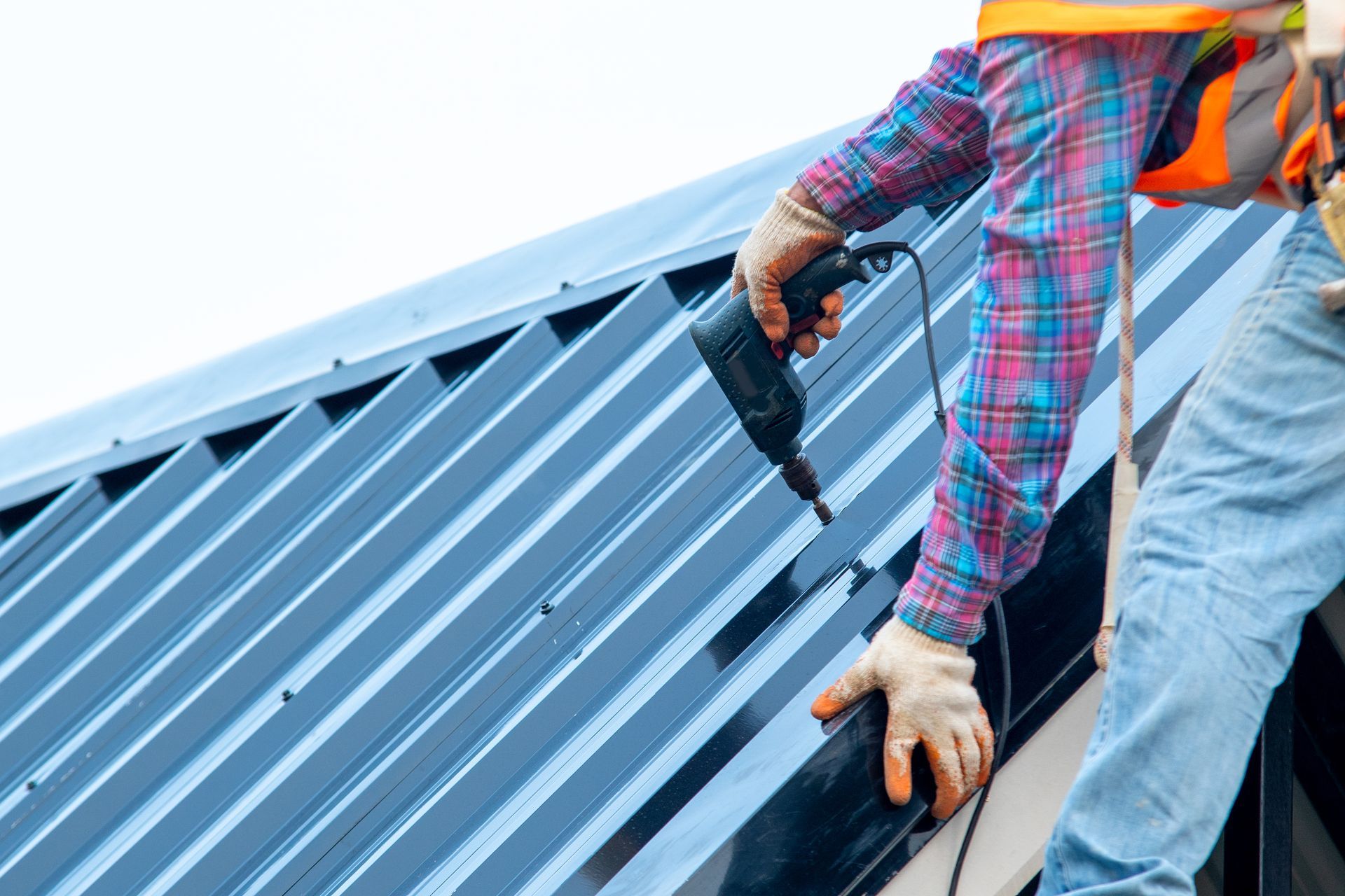 A man is using a drill to install a metal roof.