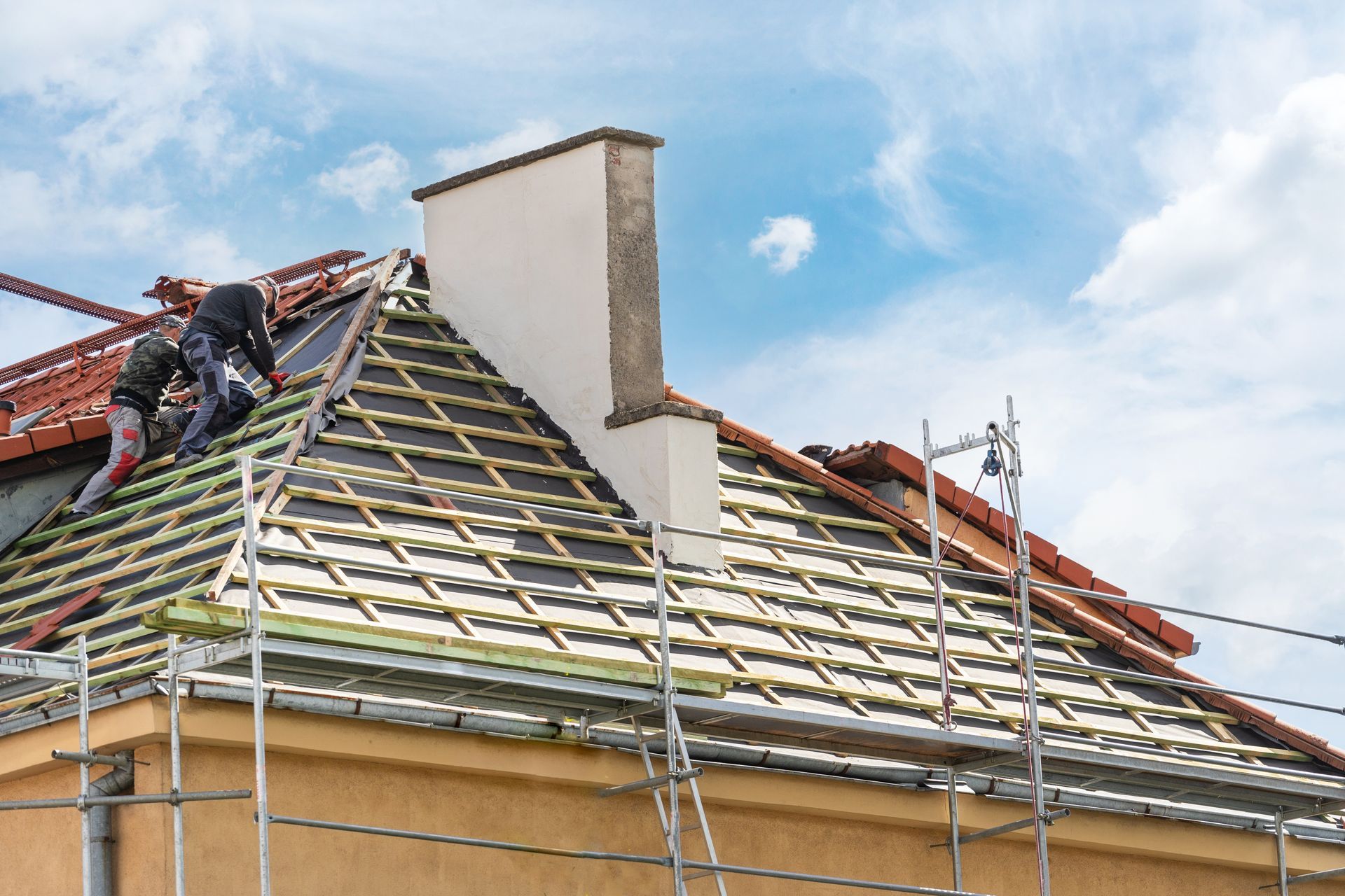 Two men are working on the roof of a house.