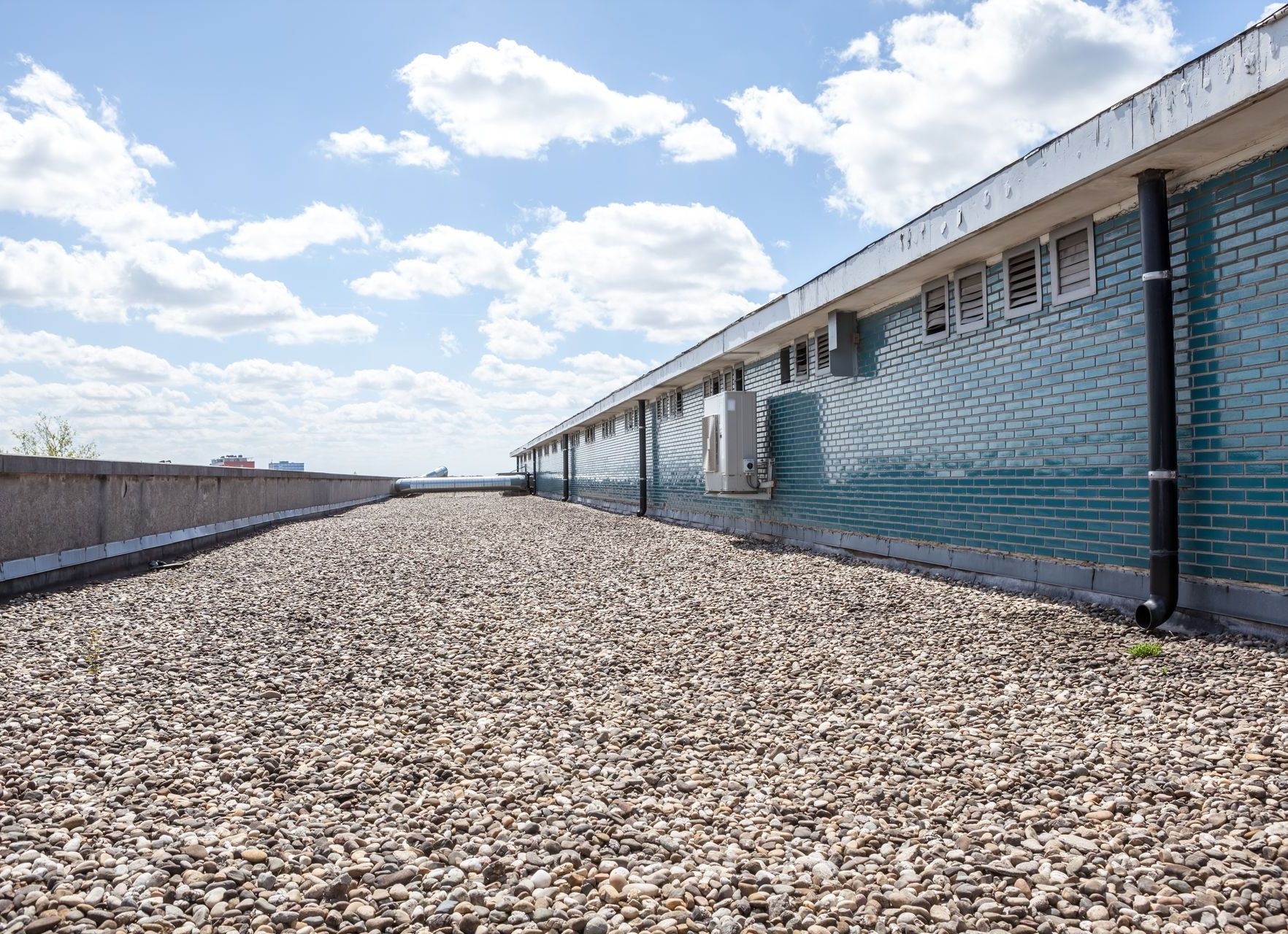 A brick building with a gravel roof and a blue sky in the background.