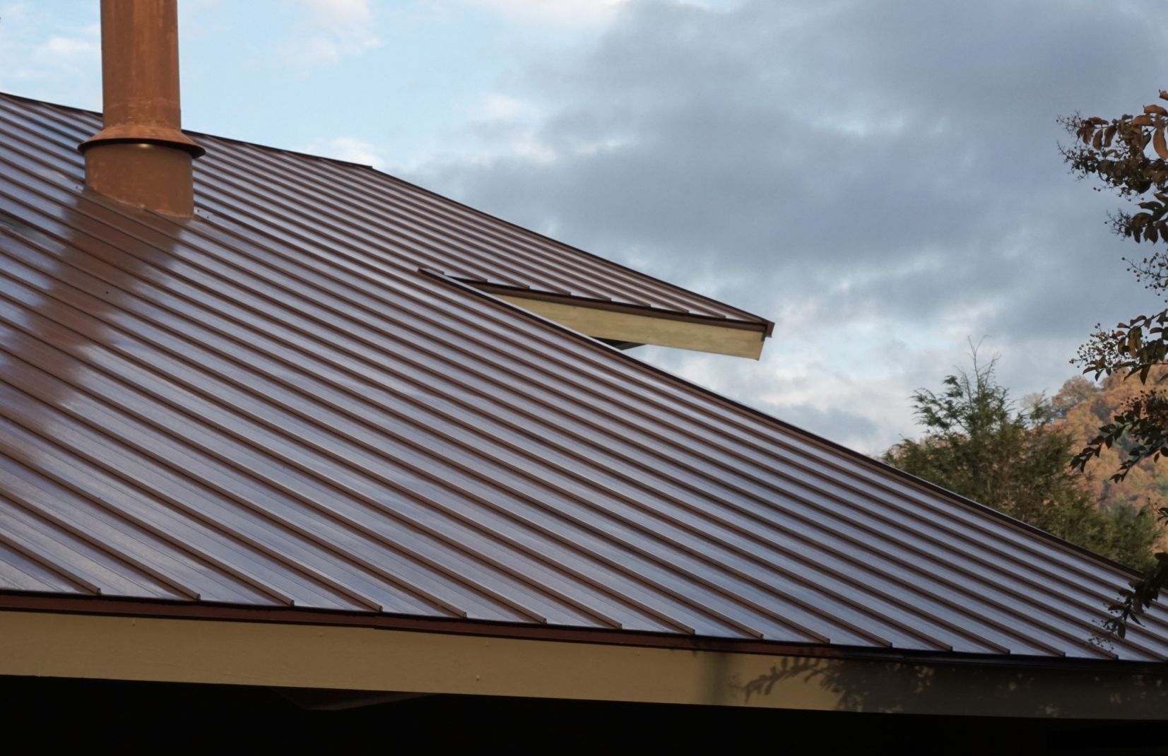 A brown metal roof with a chimney on top of it