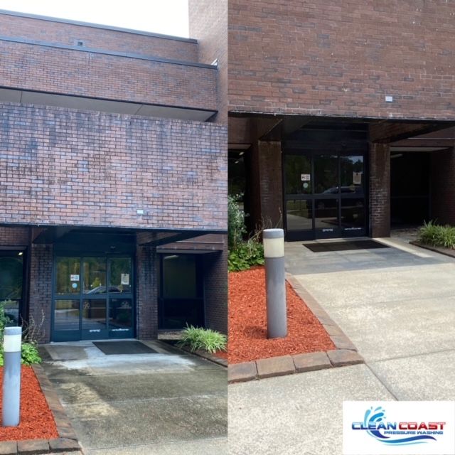 Worker wearing safety harness washes wall facade at height on modern building in a crane.