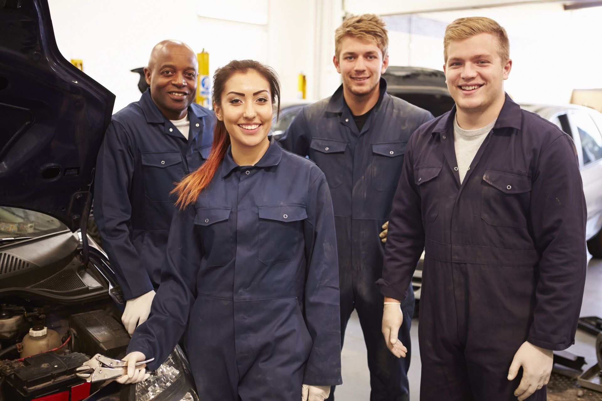A group of mechanics are posing for a picture in a garage.