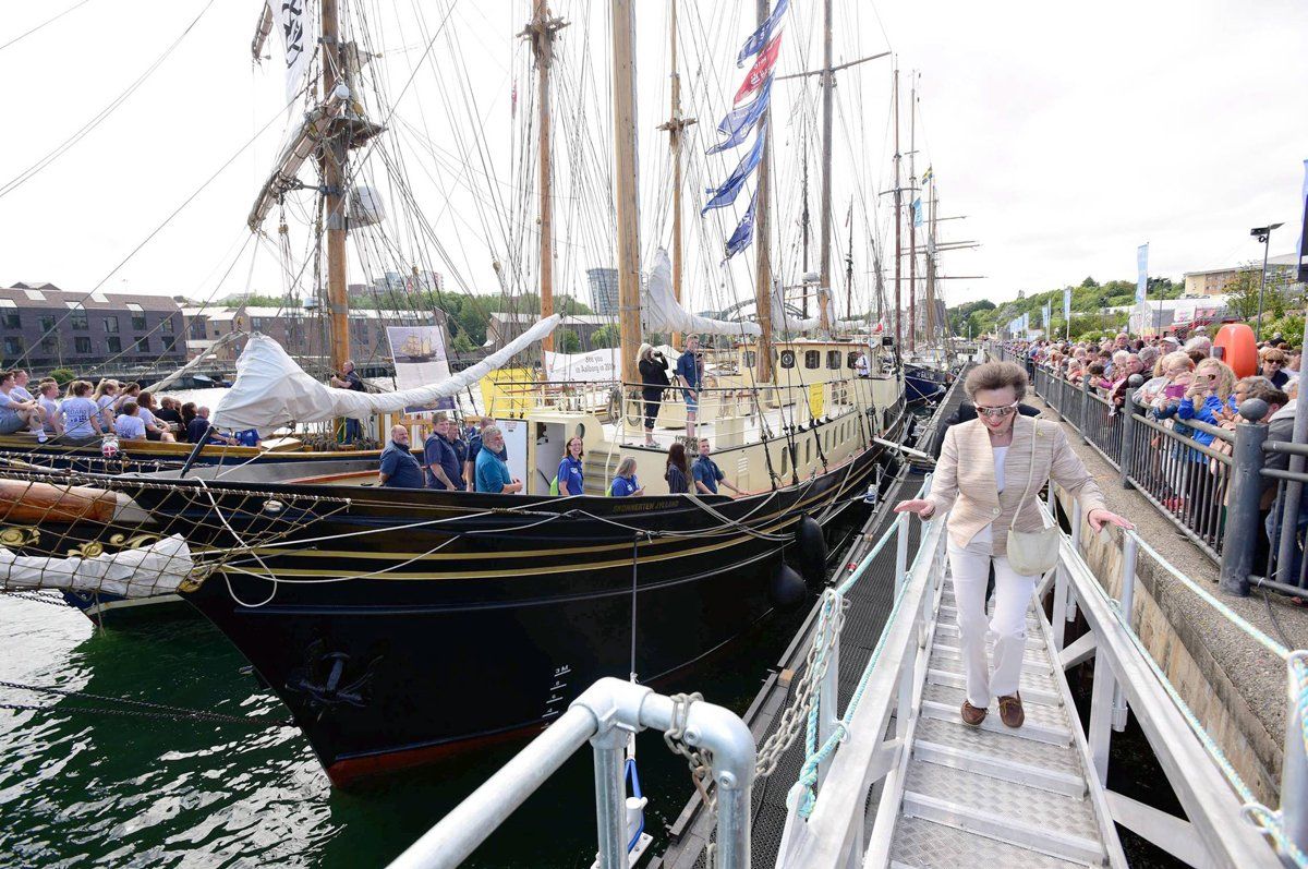 A woman is walking down stairs next to a large ship.