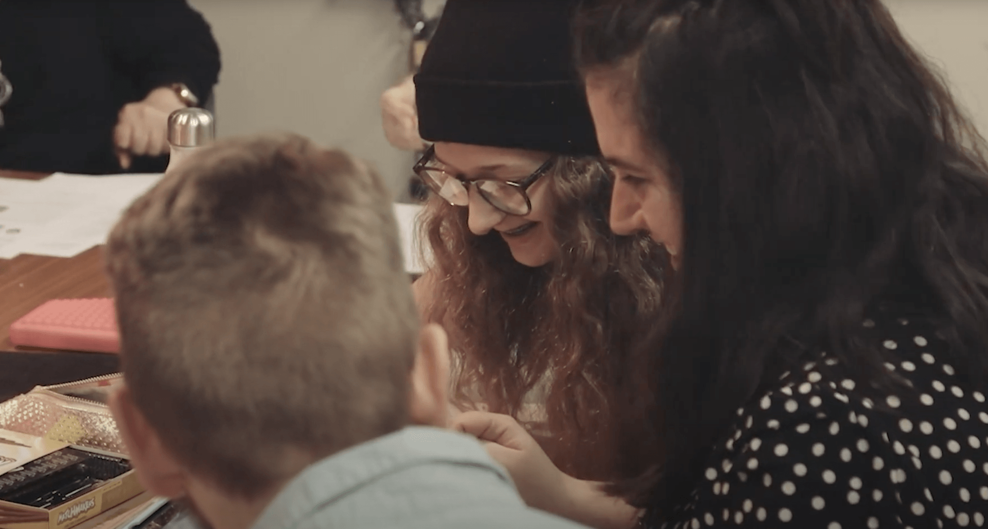 A group of people are sitting around a table looking at something.
