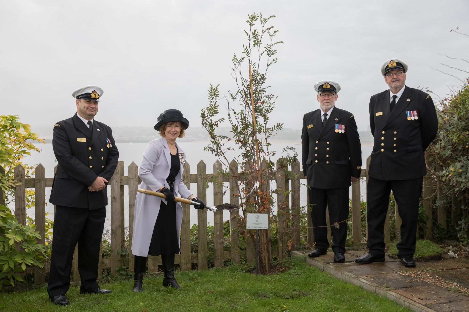 A group of people in military uniforms are standing around a tree.
