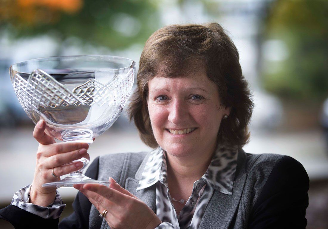 A woman is holding a trophy in her hands and smiling