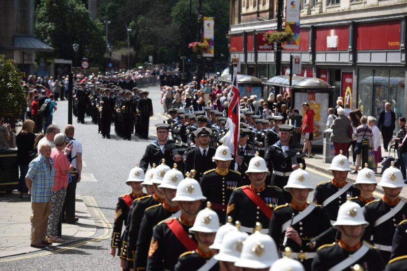 A group of soldiers marching down a street in front of a sparkasse store