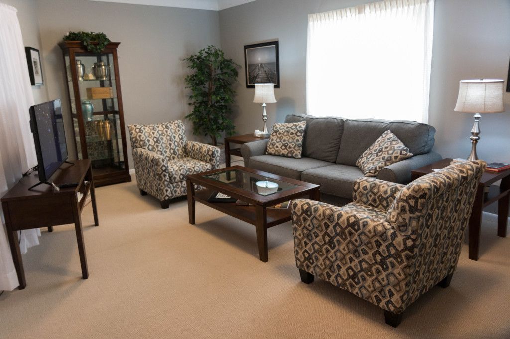 Living room with gray sofa, patterned armchairs, and a dark wood coffee table.
