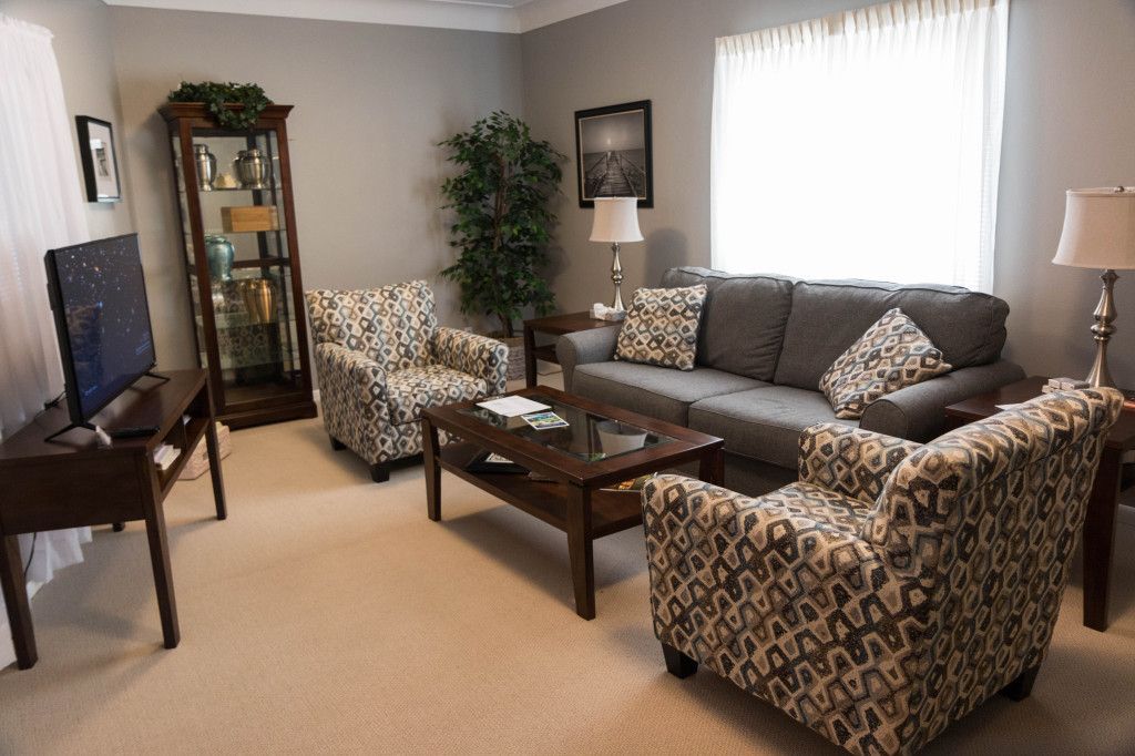 Living room with gray sofa, patterned armchairs, and a glass cabinet.
