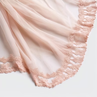 A close up of a pink veil with lace trim on a white background.