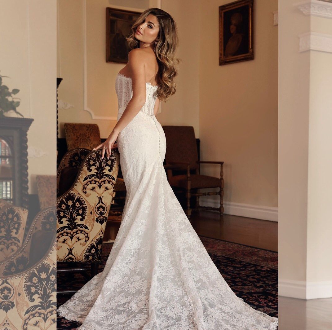 A woman in a white lace dress is standing in a living room