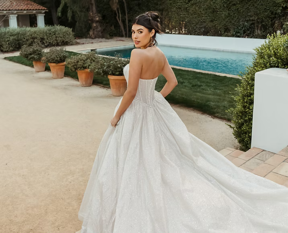 A woman in a wedding dress is standing in front of a pool.