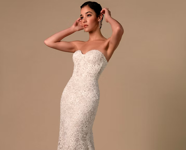 A woman is wearing a white lace wedding dress.