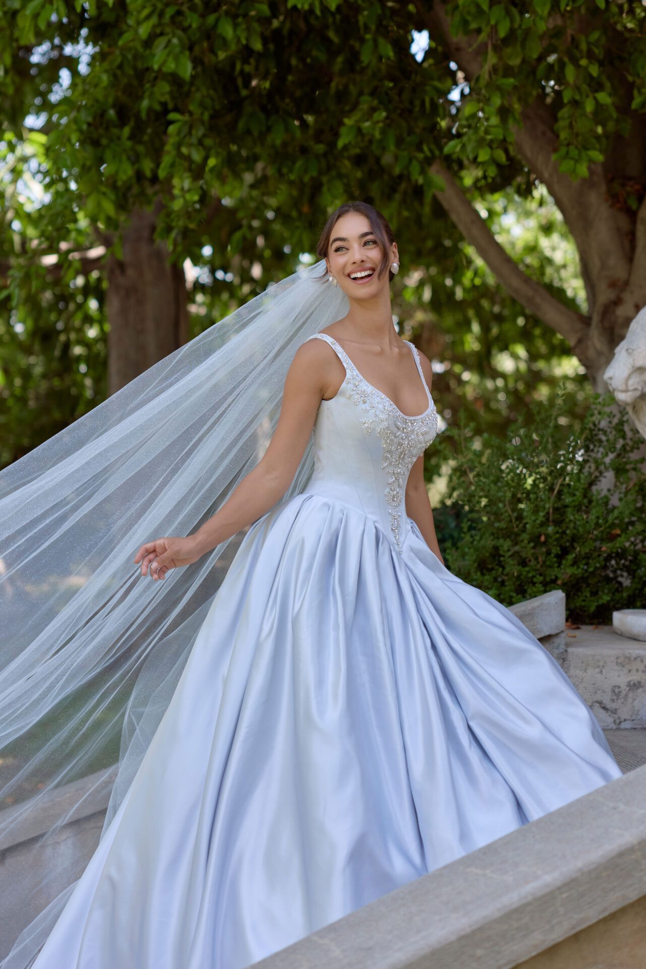 A woman in a white wedding dress is standing in front of a building.