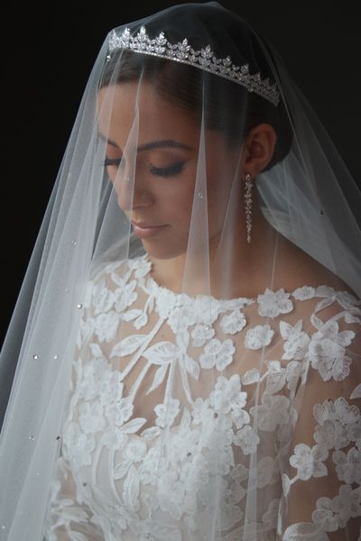 A woman in a white wedding dress and veil is standing in a room.