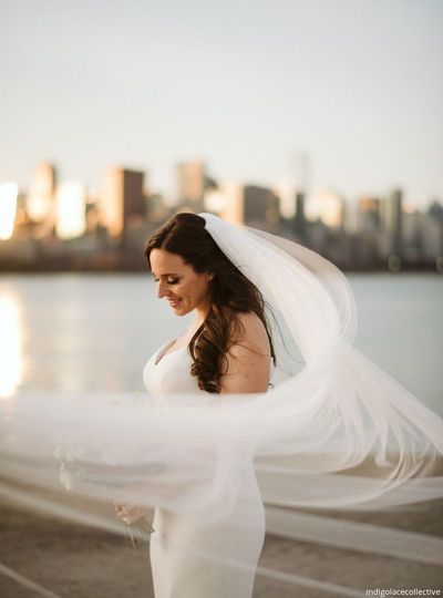 A woman in a white wedding dress is standing in front of a building.