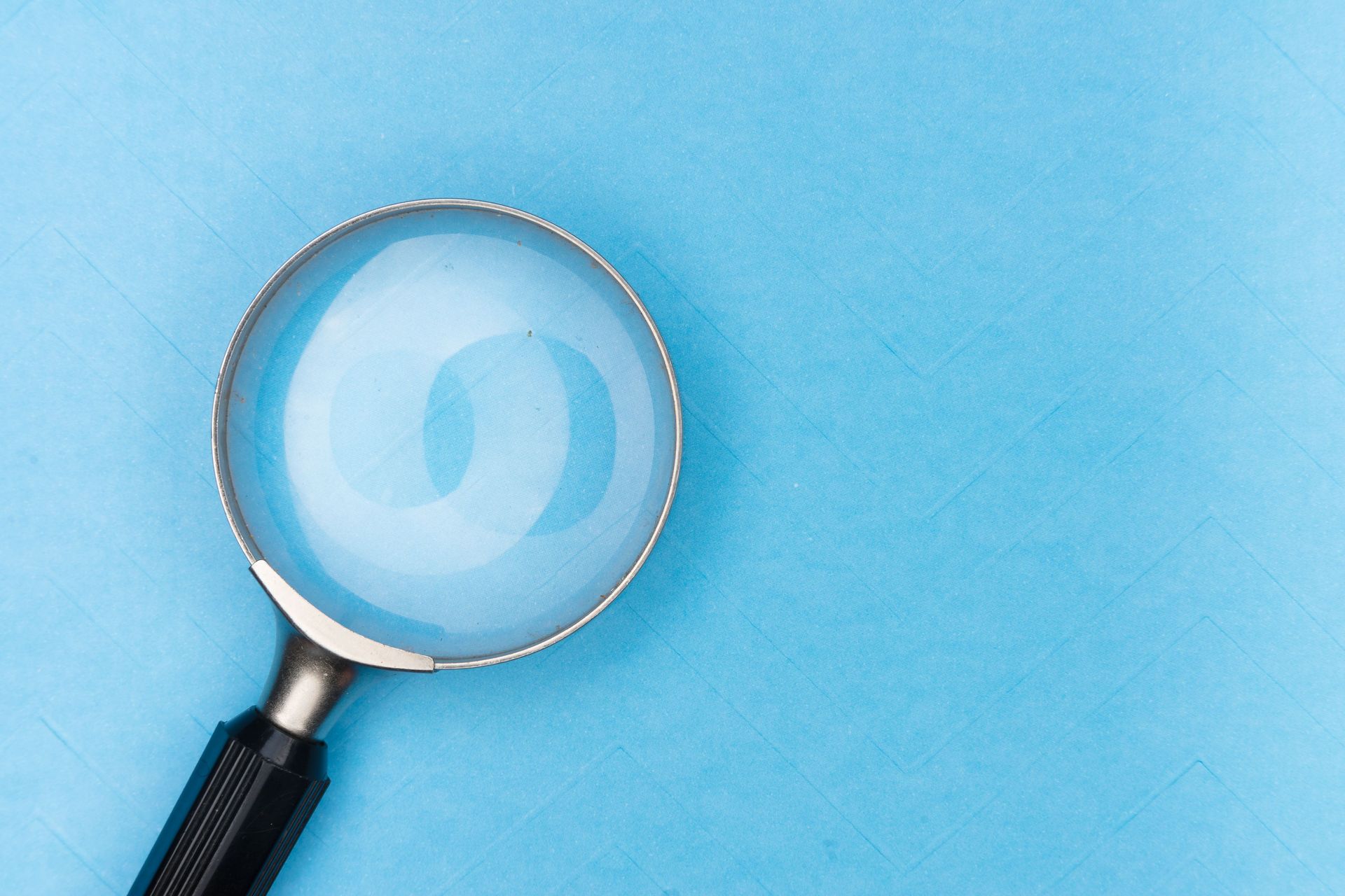 Magnifying glass with a black handle on a light blue background